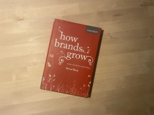 The book, How Brands Grow, lying on wooden surface.