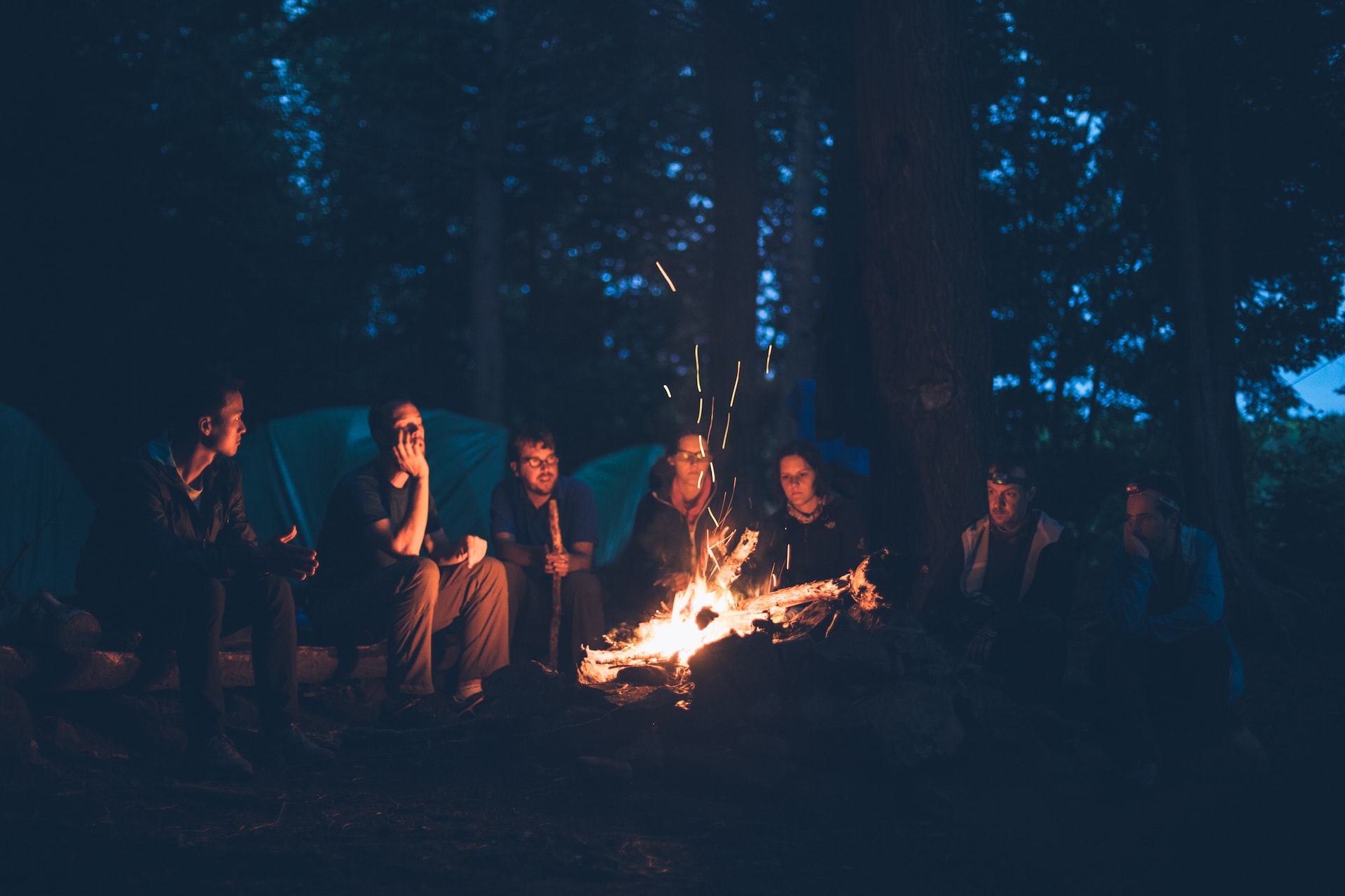 Group of friends sitting around a campfire just after sunset.