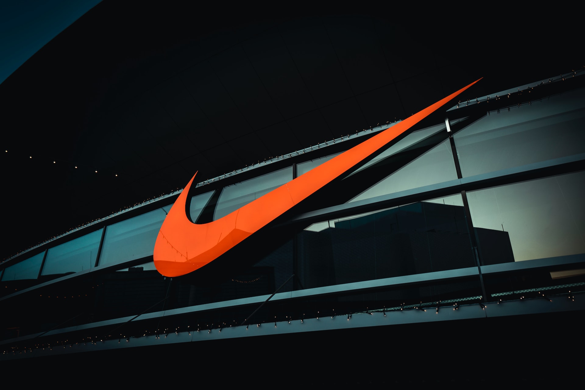 Orange Nike logo above the door of a Nike store front.